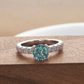 Blue green moissanite pavé solitaire ring on wood