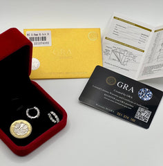 A jewelry set displayed on a white surface, including a red velvet box with a gold coin and two silver rings, alongside a gold certificate envelope, an authenticity card, and a black GRA card.