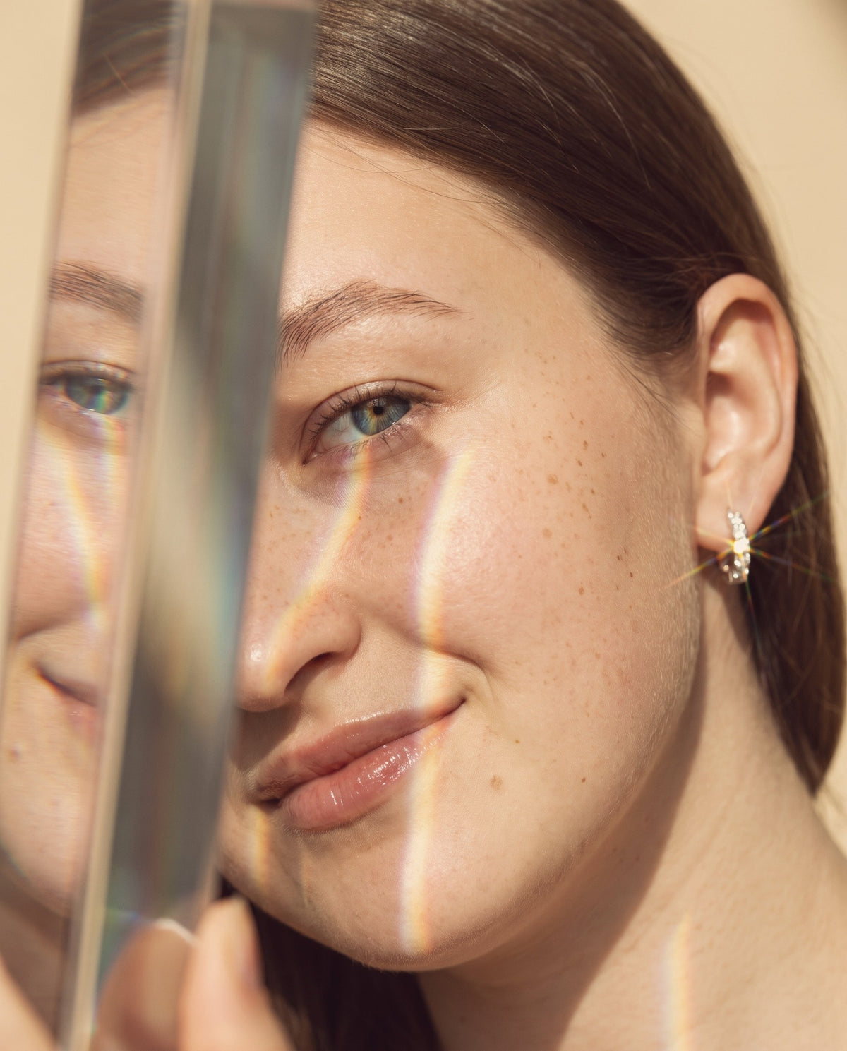 Close-up portrait in warm prism light, wearing a moissanite huggie earring