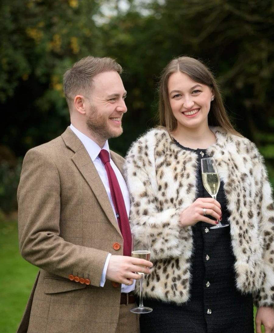 Yana and Tristan, the owners of Elle Adore, smiling with glasses of champagne in a garden