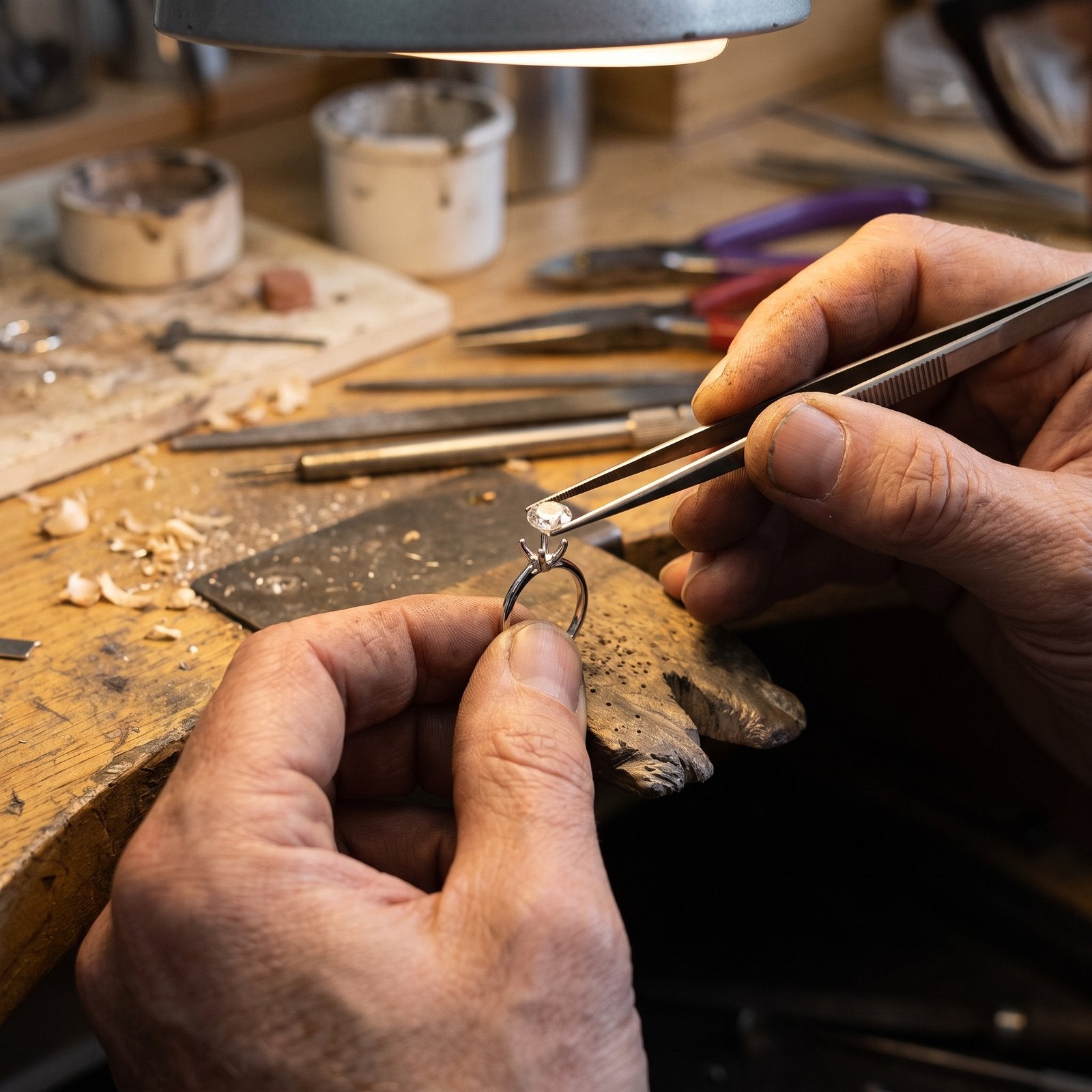 Jeweller hand-setting a stone into the sterling silver solitaire band